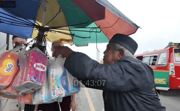 Bapak penjual tisu saat menghitung dan merapikan dagangannya untuk diserahkan kepada Jestham yang memborong seluruh barang jualannya.